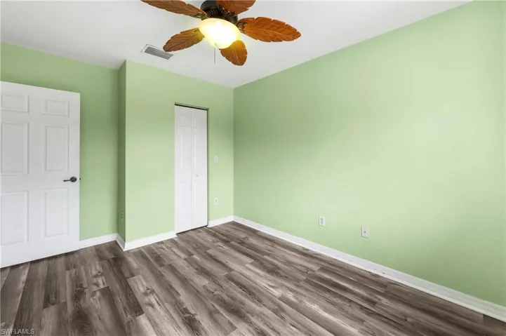 Room featuring wood-finish flooring, light green painted walls, and white trim