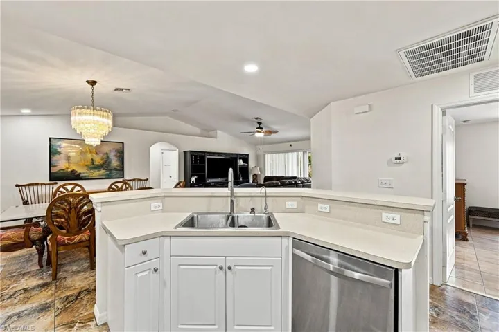 Kitchen with white cabinetry, light-toned countertop, and stainless steel dishwasher