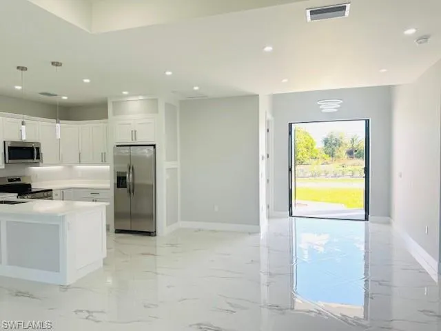 Kitchen with light marble finish floors, decorative light fixtures, appliances with stainless steel finishes, white cabinets, and recessed lighting