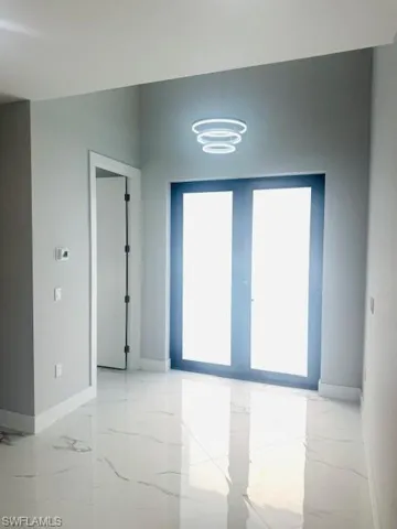 Empty room featuring french doors and light marble finish flooring