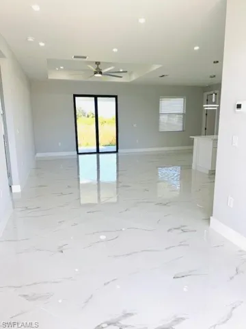 Spare room with healthy amount of natural light, a raised ceiling, recessed lighting, and a ceiling fan