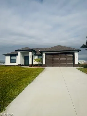 Prairie-style home featuring a front lawn, concrete driveway, a garage, roof with shingles, and stucco siding