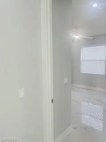Hallway featuring light marble finish floors and baseboards