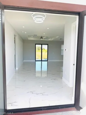 Spare room with recessed lighting, a tray ceiling, ceiling fan, and light marble finish floors