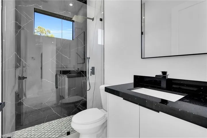 Bathroom with vanity and a marble finish shower