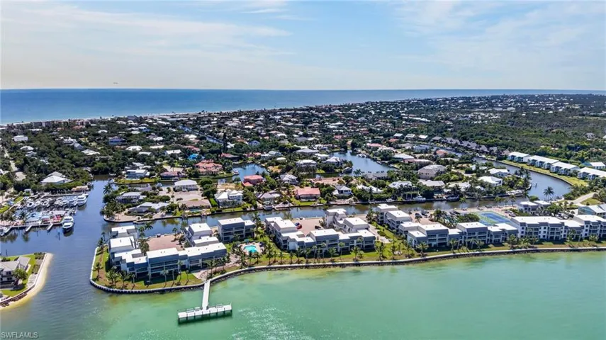 Coastal waterway setting with direct ocean access, featuring a private pier, waterfront homes, and a marina