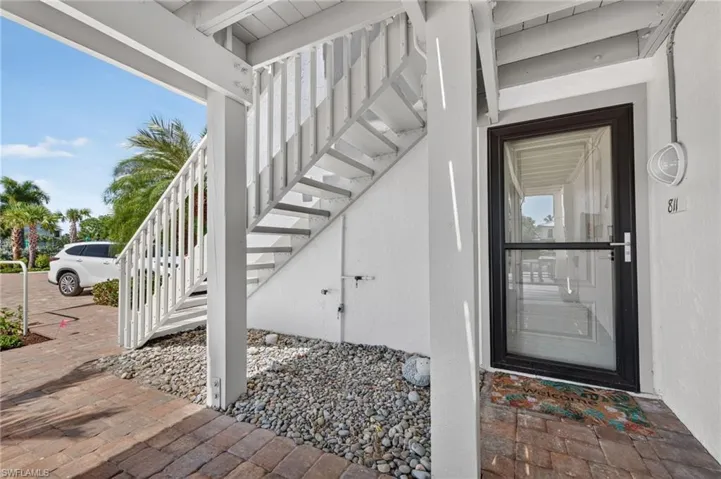 Exterior entry featuring a black storm door, white painted staircase, and paver pathway