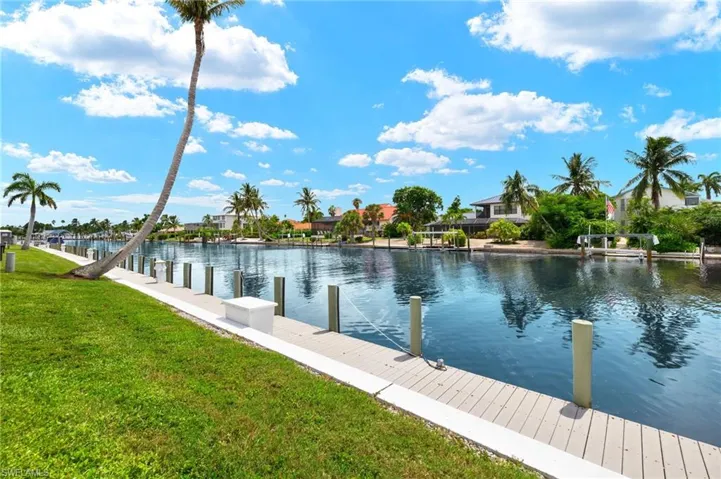 Waterfront property featuring a private dock and lush green lawn