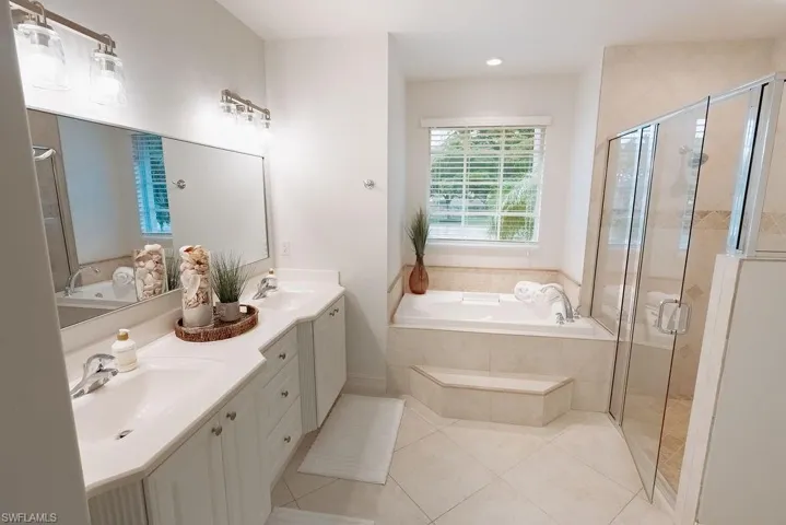 Master bathroom featuring a shower stall, a bath, and double sink vanity