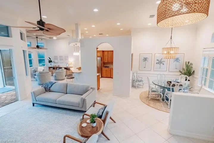 Front living room area featuring ceiling fan with notable chandelier, light tile patterned floors, arched walkways and recessed lighting
