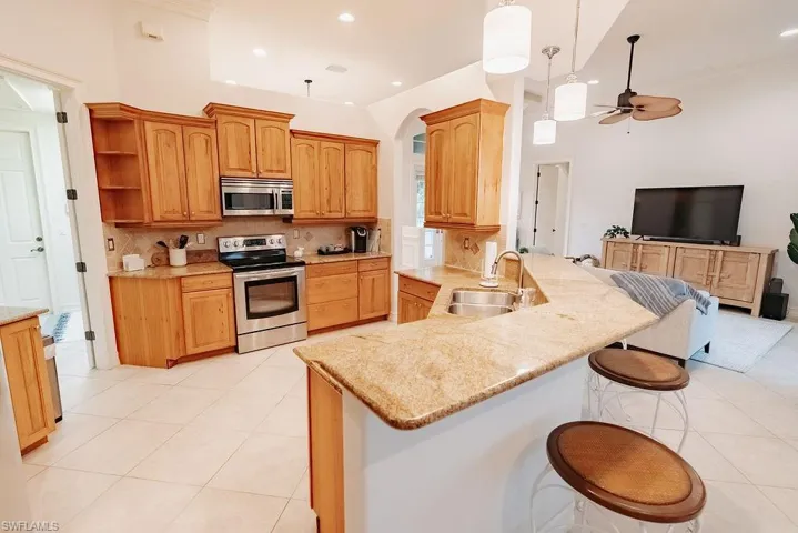 Kitchen featuring tasteful backsplash, breakfast bar with stools, stainless steel appliances, and double sink