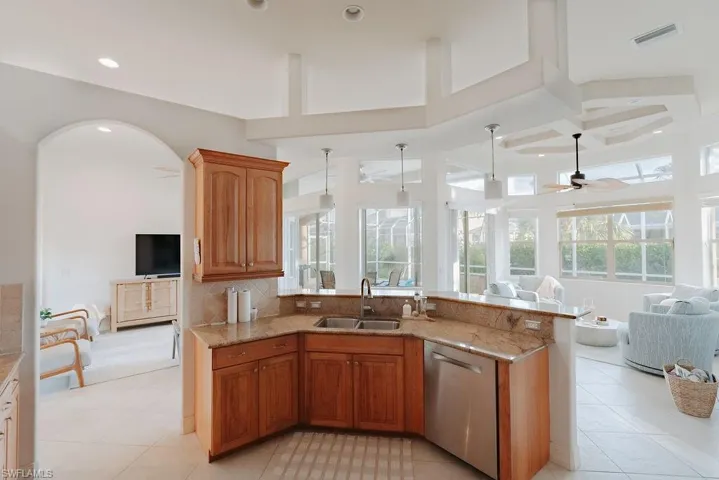 Kitchen featuring stainless steel dishwasher, light stone countertops, double sink, recessed lighting and open floor plan