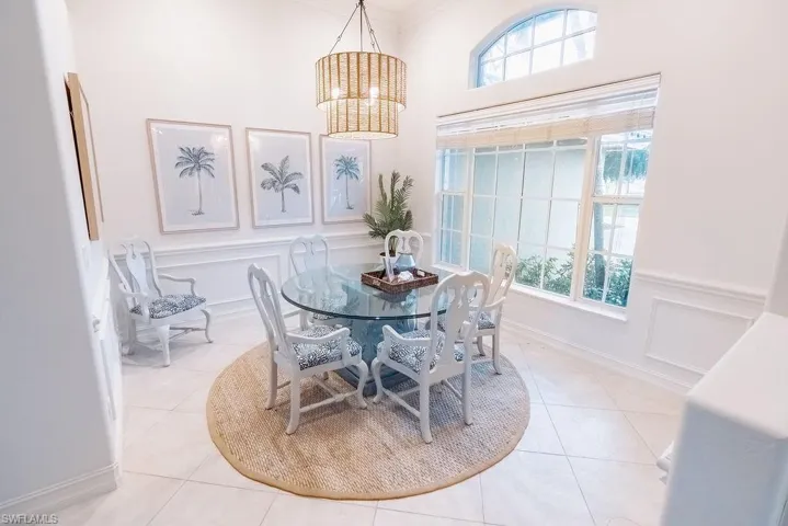 Dining area with a decorative wall, tile patterned floors, a wealth of natural light, and an inviting chandelier