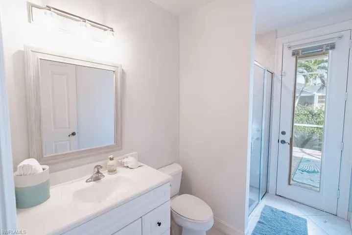 Guest/Pool Bathroom featuring tile patterned floors, toilet, a stall shower, and vanity