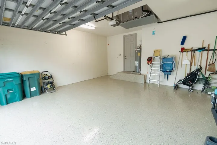Garage featuring a garage door opener and electric water heater