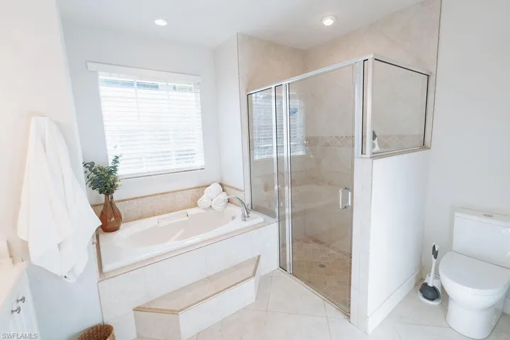 Master bathroom featuring vanity, a stall shower, tile patterned flooring, toilet, and a bath