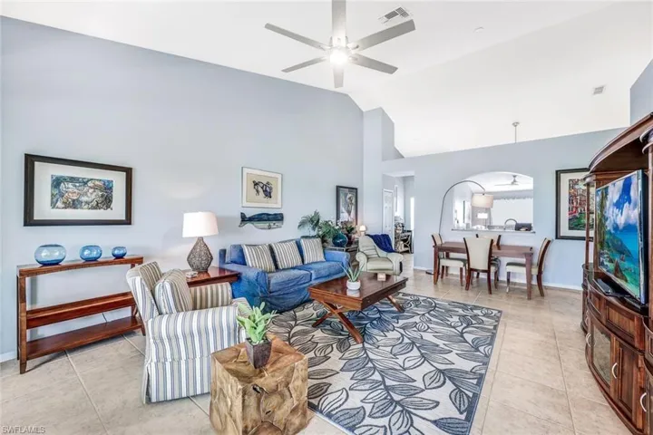 Living room featuring ceiling fan, high vaulted ceiling, and light tile patterned flooring