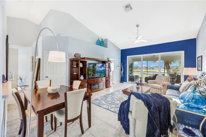 Tiled living room with ceiling fan and high vaulted ceiling