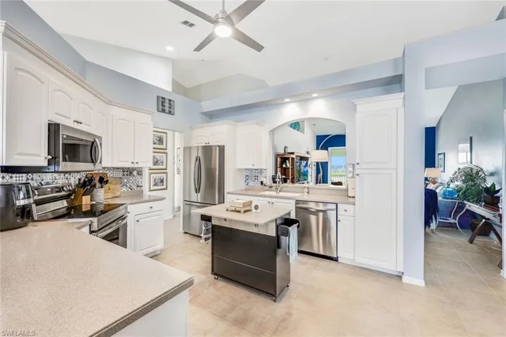 Kitchen with appliances with stainless steel finishes, lofted ceiling, ceiling fan, a kitchen island, and decorative backsplash