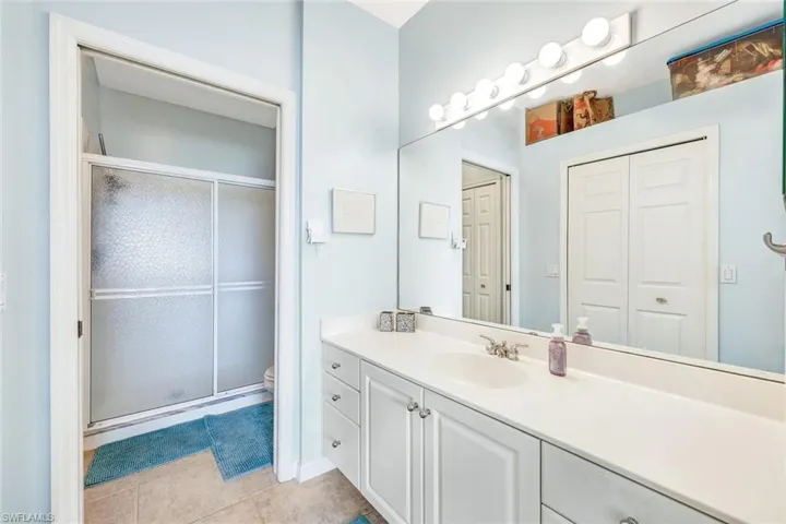 Bathroom featuring tile patterned floors, toilet, a shower with door, and vanity