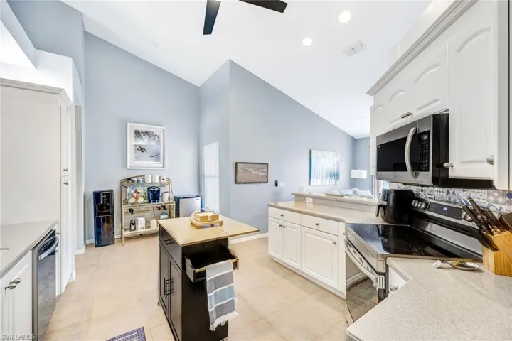Kitchen featuring backsplash, stainless steel appliances, white cabinetry, ceiling fan, and light tile patterned flooring