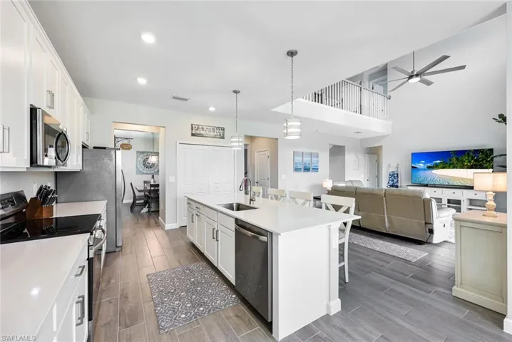 Kitchen with sink, white cabinetry, stainless steel appliances, a center island with sink, and ceiling fan