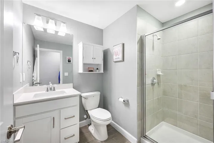 Bathroom with hardwood / wood-style floors, vanity, toilet, and a shower with door