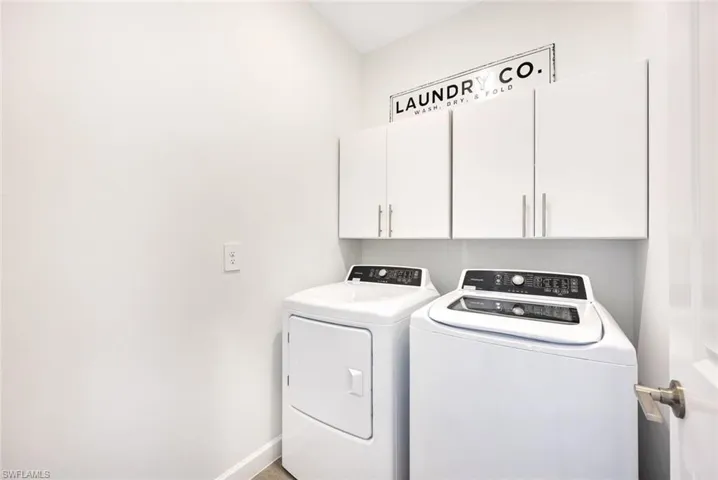 Laundry room featuring washing machine and clothes dryer and cabinets