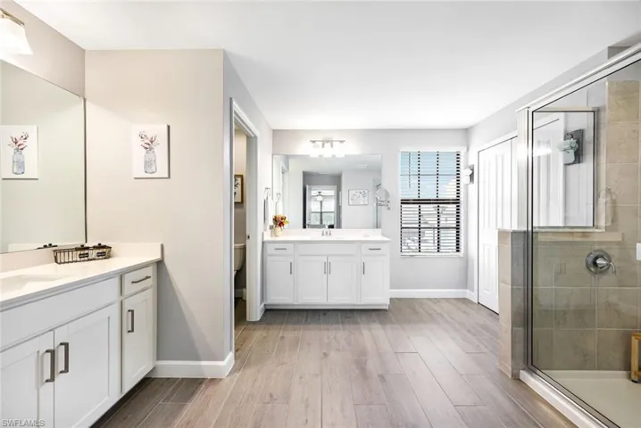 Bathroom with wood-type flooring, vanity, and a shower with shower door
