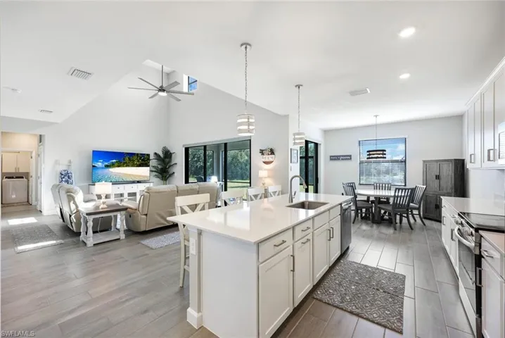 Kitchen featuring a healthy amount of sunlight, a center island with sink, ceiling fan, and white cabinets