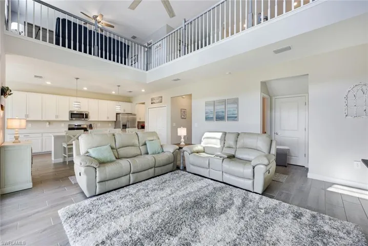 Living room with ceiling fan, light hardwood / wood-style flooring, and a towering ceiling