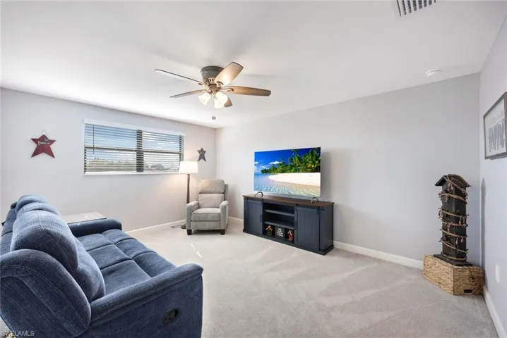 Living room with ceiling fan and light colored carpet