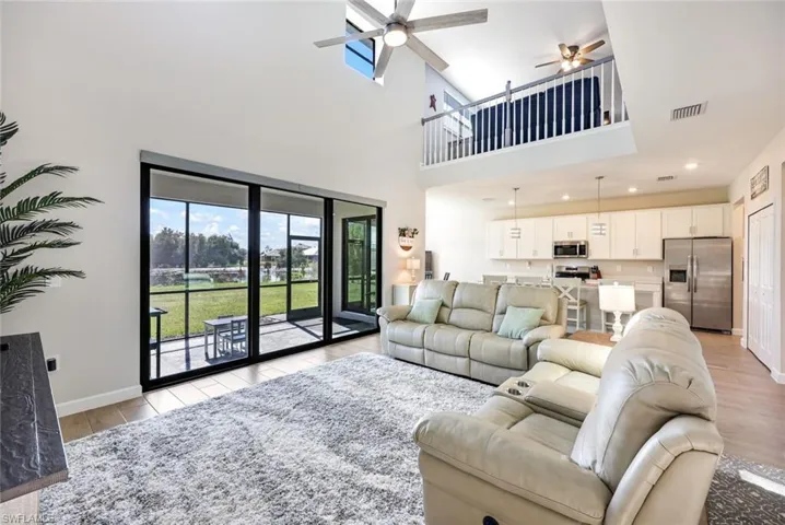 Living room featuring light wood-type flooring, a high ceiling, and ceiling fan