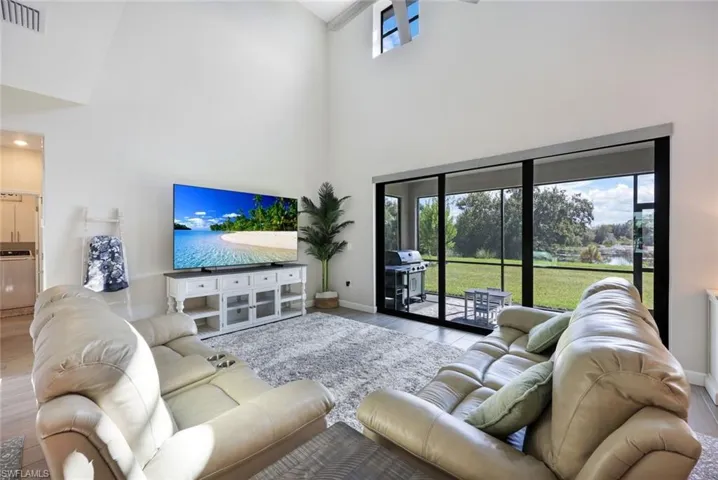 Living room with a healthy amount of sunlight, light hardwood / wood-style floors, and high vaulted ceiling