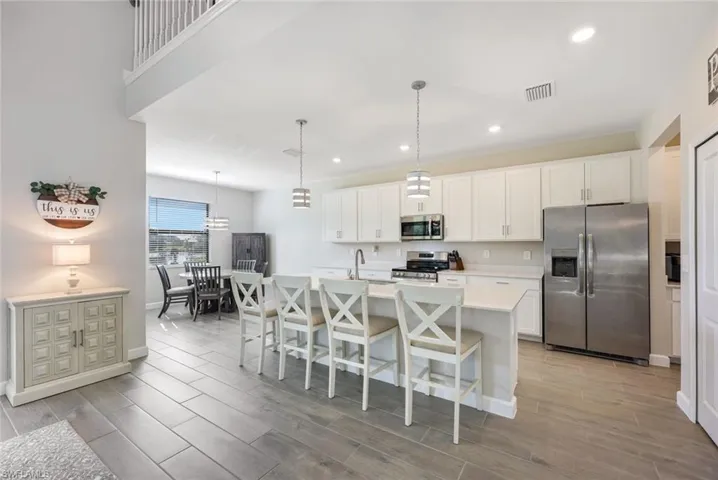Kitchen with a kitchen island with sink, appliances with stainless steel finishes, and white cabinetry
