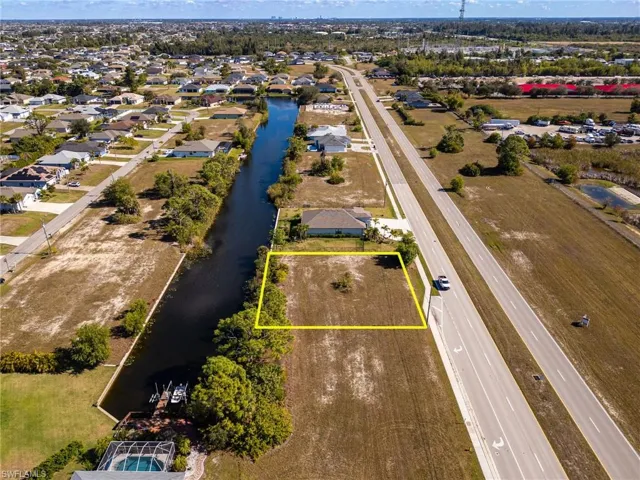 Aerial perspective of suburban area with property parcel outlined and a nearby body of water