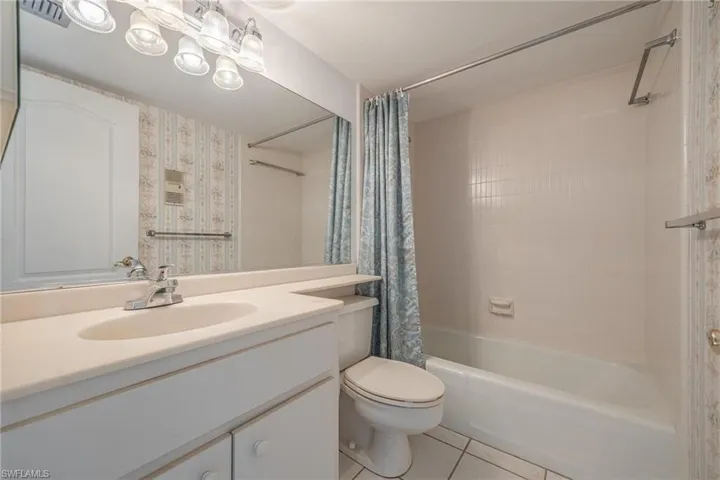 Full bathroom with vanity, shower / tub combo, tile patterned flooring, and toilet