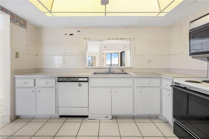 Kitchen with white cabinetry, light tile patterned floors, and white appliances