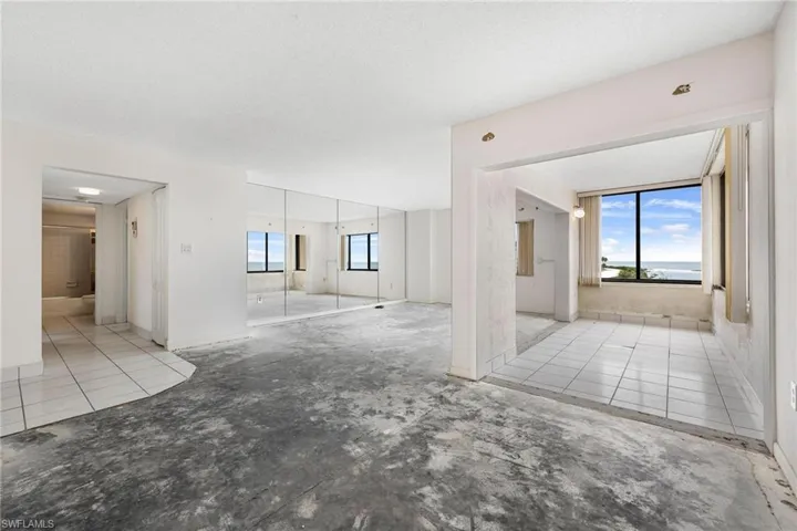 Tiled empty room with a textured ceiling and a healthy amount of sunlight