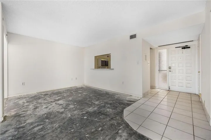 Unfurnished living room featuring a textured ceiling and light tile patterned floors