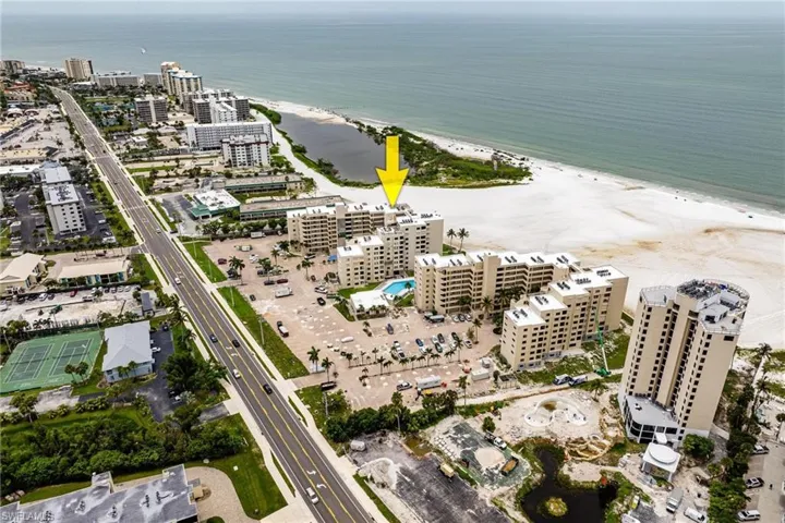 Birds eye view of property featuring a water view and a view of the beach