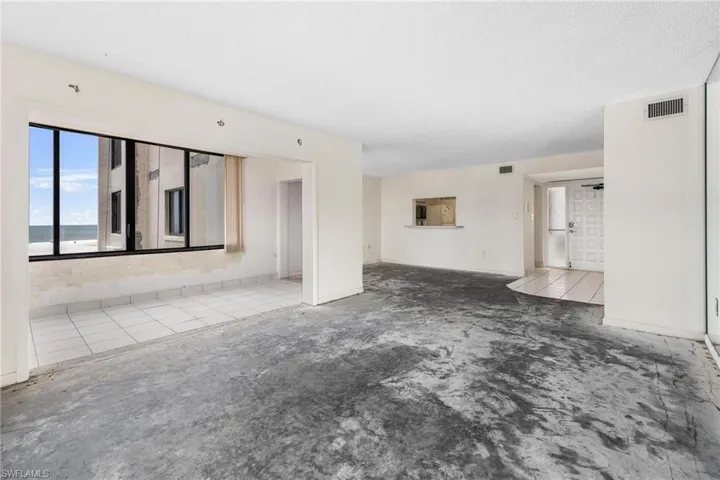 Unfurnished living room with a water view, a textured ceiling, and tile patterned flooring