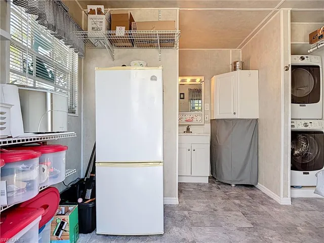 Laundry room featuring stacked washer and dryer and baseboards