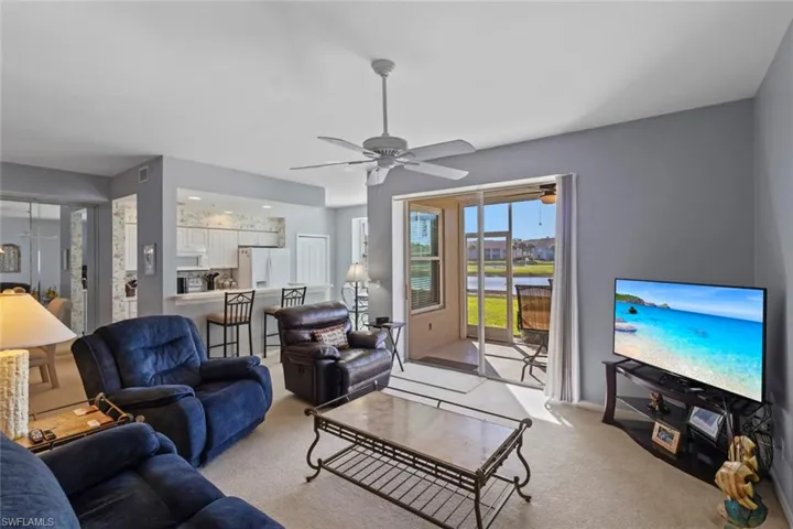 Well lit living room with sliders to back lanai, overlooking the lake and golf course