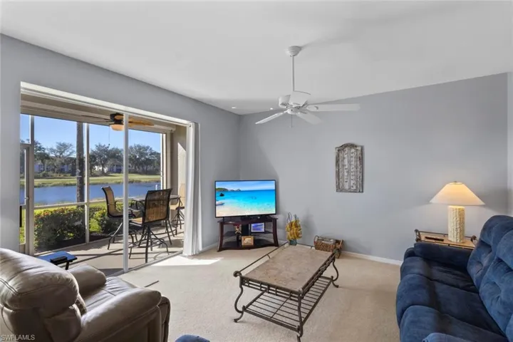 Well lit living room with sliders to back lanai, overlooking the lake and golf course