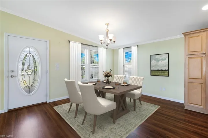 Dining room featuring a chandelier, plenty of natural light, ornamental molding, dark wood-type flooring, and baseboards
