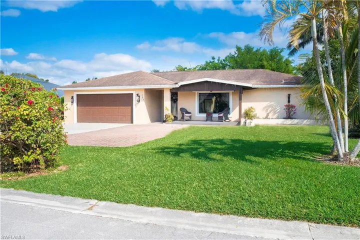 Ranch-style home featuring stucco siding, a porch, a front lawn, driveway, and a garage