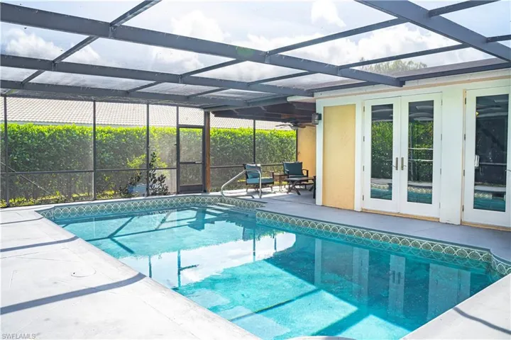 Outdoor pool featuring glass enclosure, a patio, french doors, and a sunroom