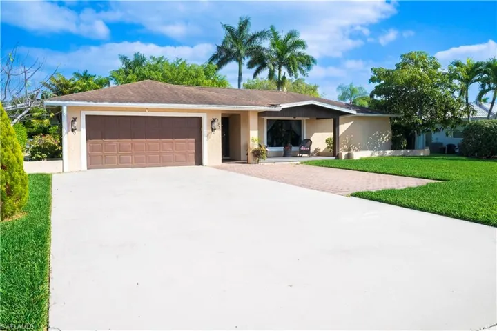 Ranch-style home with stucco siding, driveway, a front lawn, and an attached garage