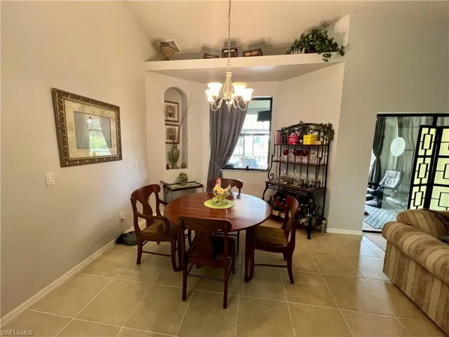 Dining area with a high ceiling, a chandelier, and tile patterned floors